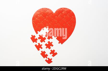 Heart shaped jigsaw puzzle with scattered pieces on white background Stock Photo