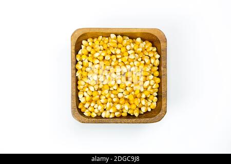 Seeds of golden corn popcorn in a wooden bowl close-up on a white background isolated Stock Photo