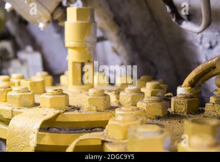 Fragment fastening plate with a lot of bolts with nuts covered with yellow paint close-up Stock Photo