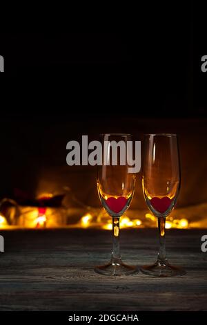 Two empty wine glasses on the background of burning lights with hearts. Stock Photo