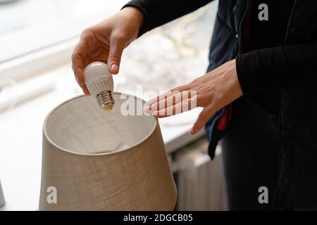 Woman hand replacing light bulb for energy saving one. Energy efficiency at home Stock Photo