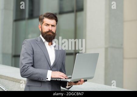 Web conferencing. Serious engineer use laptop outdoors. Computer conference. Making video call. Video conference. Modern technology. Formal fashion style. Business communication. Stock Photo
