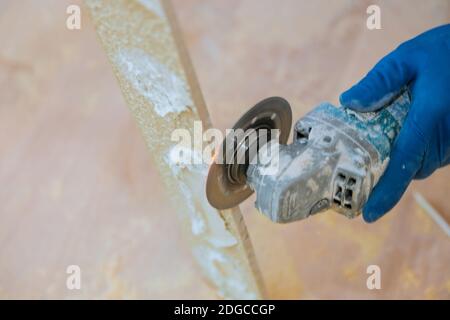 A construction worker cutting a tile using grinder Stock Photo