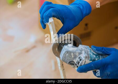 Worker cutting a tile using grinder at construction trimming tiles Stock Photo