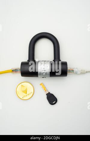 Two computer network cables going through a lock with a key and a crypto currency coin Stock Photo