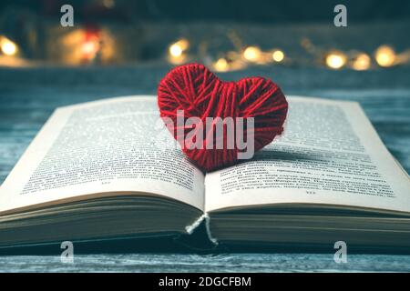 A book with a red heart on a dark background with lights. Stock Photo
