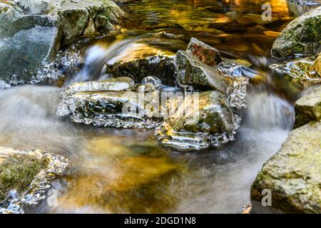 Beautiful waterfall in the winter. Rocks covered by ice,  surround the water Stock Photo