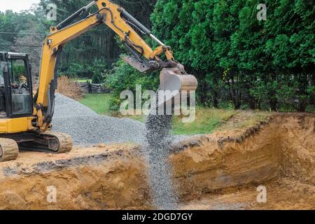 A yellow excavator bucket shovel moving stones gravel of foundation on a construction site Stock Photo