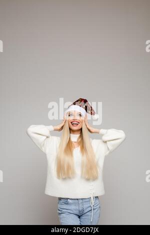 Happy young Caucasian Santa lady in white sweater Stock Photo