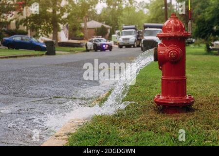 Water flowing from an open red fire hydrant is wet from the spray. Stock Photo