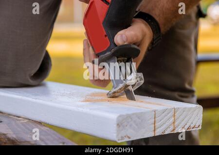 Carpenter using jigsaw for cutting wooden boards with power tools. Stock Photo