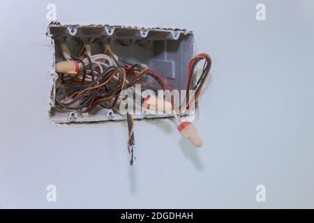 Unfinished electrical mains outlet socket with electrical wires and connector installed in plasterboard drywall for gypsum walls Stock Photo