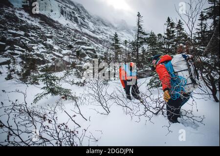 Two alpine climbers walk through deep snow while headed to a climb Stock Photo