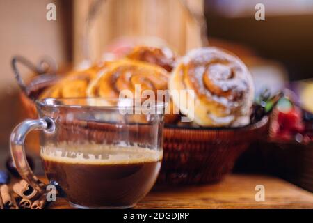 Black coffee and cinnamon buns on wooden table. Stock Photo