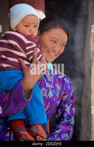 Ladakhi mother in festive dress carrying young child. Karsha Gustor festival, Karsha monastery, near Padum Zanskar Valley, Ladakh, Jammu and Kashmir, northern India Stock Photo