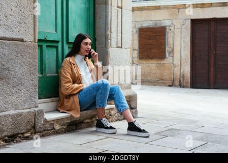 Young beautiful woman sitting outdoors and talking on phone Stock Photo