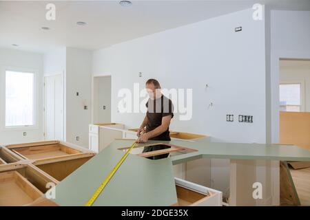 Man using tape measure for measuring size of wooden countertop in modern kitchen for home improvement. Stock Photo