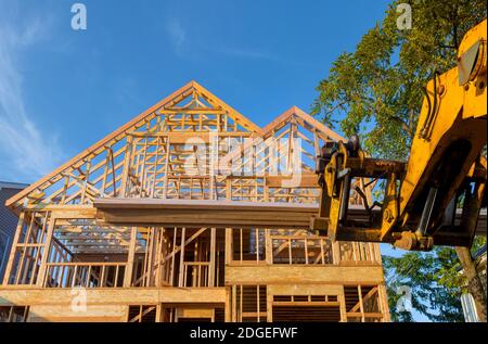 Heavy boom truck machinery is used to add the roof trusses to a timber frame house extension Stock Photo