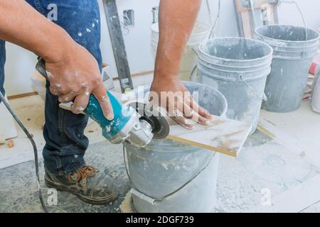 A construction worker cutting a tile using grinder Stock Photo