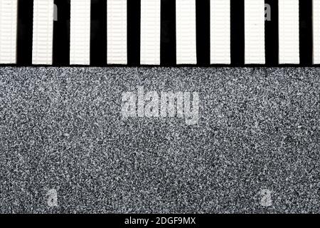 The surface texture of the marble remnants finish flooring and the plastic gutter cover beside the pool Stock Photo
