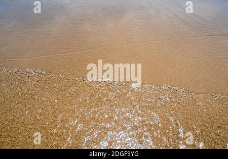 Light reflection on the surface of movement sea on sand beach Stock Photo