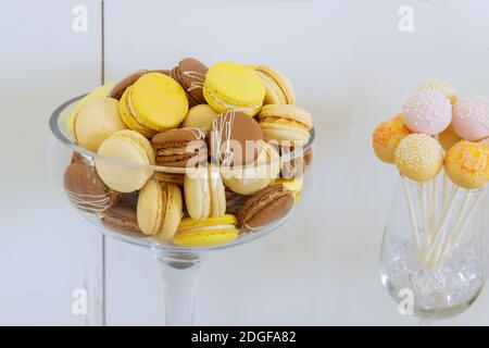 Pastel, yellow and brown color macaroons in a glass bowl. French dessert. Stock Photo