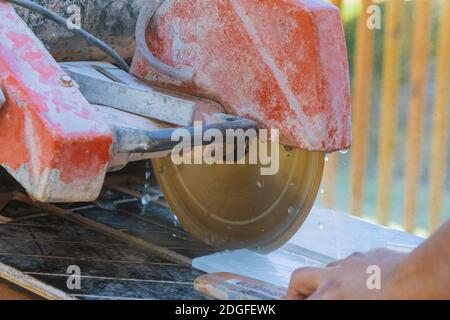 Builder in cutting tiles with big electro saw on the construction Stock Photo