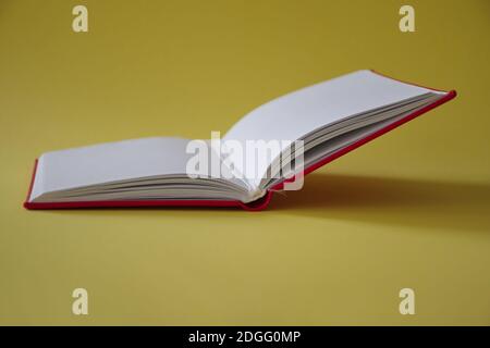 Open red notebook on yellow background Stock Photo