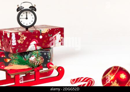 santa claus sleigh, alarm clock, santa claus staff, golden christmas tree cone and boxes with gifts on a white wood background with gold veins Stock Photo