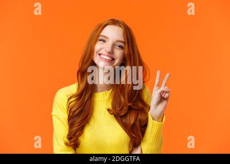 Waist-up cheerful gorgeous redhead woman with long curly red hair, showing peace sign and smiling happily, express positivity, l Stock Photo