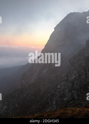 Majestic landscape with high rocks and dramatic cloudy sky at sunrise. Nature background. Carpathian Mountains,Fagaras,Romania. Stock Photo