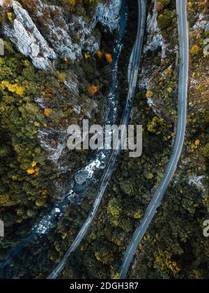 Aerial view of winding road with blue lake. Road trough autumnal forest Lake Prisaca,Romania. Stock Photo