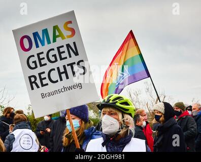 Braunschweig, Germany, December 05., 2020: An elderly woman with a bicycle helmet and a face mask holds up a poster of grannies against the right fasc Stock Photo