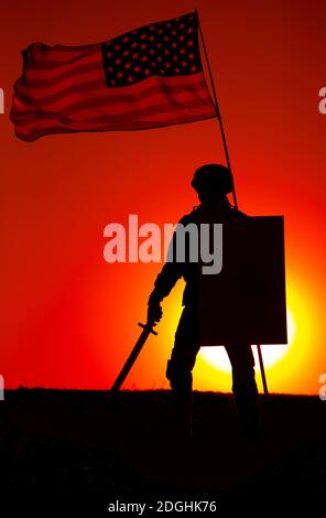 Silhouette of American army soldier armed sword and shield standing under waving US national flag on background of sunset. Army hero and patriot, military glory and honor, fallen soldiers remembrance Stock Photo