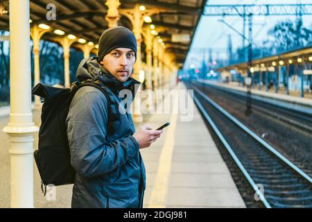 Sopot Fast Urban Railway station. young man standing and waiting train on platform. tourist travels by train. Portrait Of Caucas Stock Photo