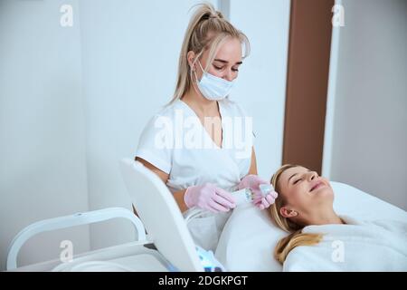 Focused dermatologist preparing for treating her patient Stock Photo