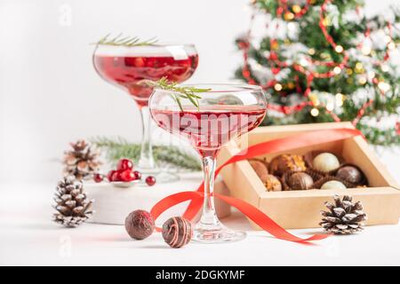 Winter drink cocktail from cranberry rosemary in two elegant glasses on a white background box of chocolates. Christmas or New Year's table setting. F Stock Photo