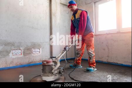 Worker performing and polishing sand and cement screed floor Stock Photo