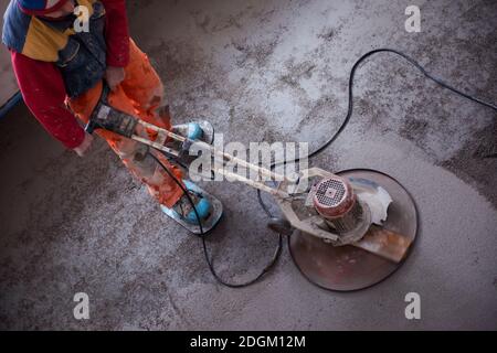 Worker performing and polishing sand and cement screed floor Stock Photo