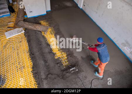 Worker performing and polishing sand and cement screed floor Stock Photo