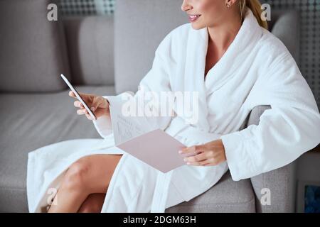 Pleased female spa client using her smartphone Stock Photo
