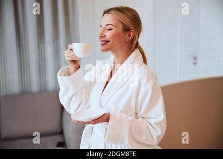 Smiling spa client holding a cup of fragrant beverage Stock Photo