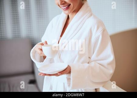 Joyous female enjoying her herbal tea in a beauty salon Stock Photo