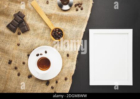 A cup full of espresso with chocolate and coffee beans and candles and a picture frame. Flat lay overhead shot. Stock Photo