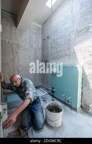 Worker using level tool while installing big ceramic tiles Stock Photo