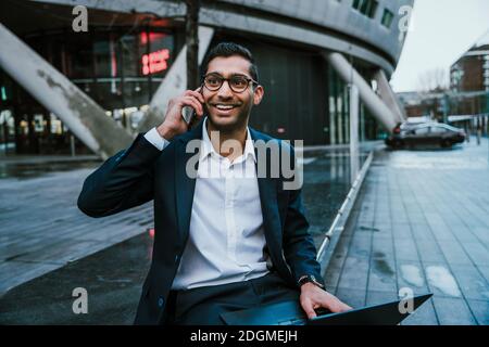 Mixed race businessman chatting on cellular device taking lunch break from work Stock Photo