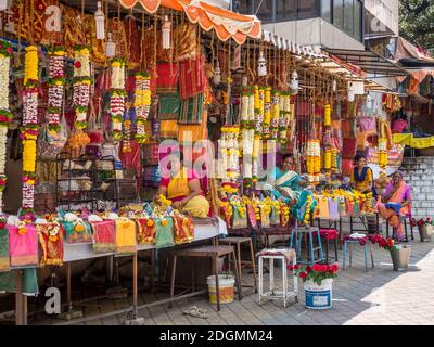 PUNE, INDIA - MARCH 14, 2019: Indian women in traditional dress sell religious bundles of flowers in the colorful stalls in Pune, India Stock Photo