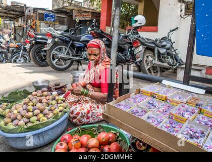 PUNE, INDIA - MARCH 14, 2019: Indian woman in national dress selling fruits and souvenirs in Pune, India Stock Photo