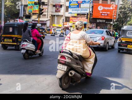 PUNE, INDIA - MARCH 14, 2019: Women on mopeds on a busy street in Pune, state Maharashtra, India Stock Photo