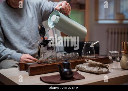 https://l450v.alamy.com/450v/2dgn16m/brewing-delicious-strong-chinese-tea-stage-of-a-real-oriental-tea-ceremony-at-home-with-a-special-set-of-bamboo-tools-the-tea-master-pours-hot-water-into-a-bowl-2dgn16m.jpg